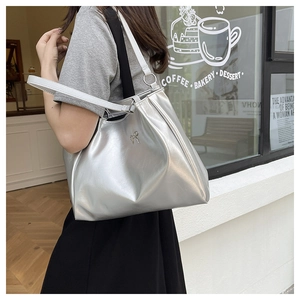 Close-up of shiny silver metallic tote bag with elegant silver bow detail and dual straps