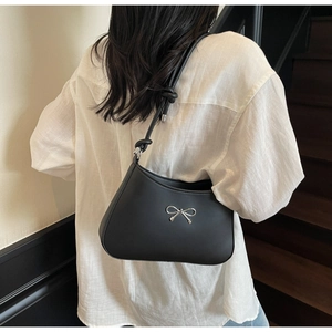 Detail of black matte shoulder bag with silver bow buckle and trendy knotted strap design