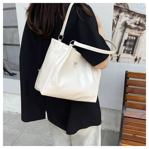 Détail d'un grand sac cabas blanc cassé en cuir avec un nœud en métal sur un modèle