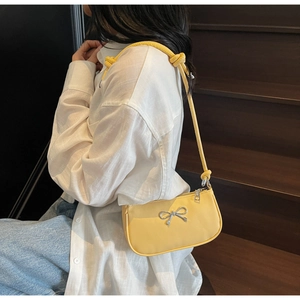 Detail of yellow leather crescent bag with silver metal bow and knotted shoulder strap