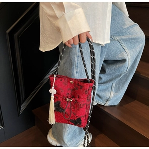 Detail of red brocade bucket bag with embroidered butterfly and white tassel charm