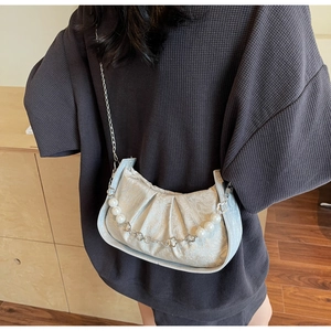 Detail of a pearl chain crossbody cloud bag with floral embossed texture and pleated design