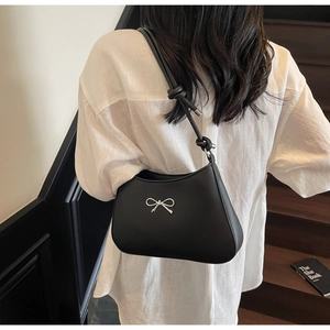 Detail of black faux leather underarm bag with silver bow and knotted shoulder strap detail