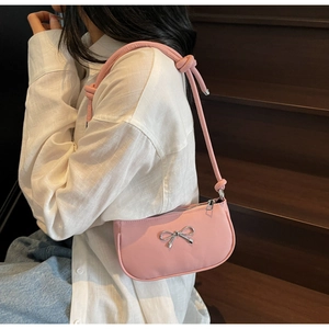 Pink crescent underarm bag with a silver bow knot detail and knotted shoulder strap
