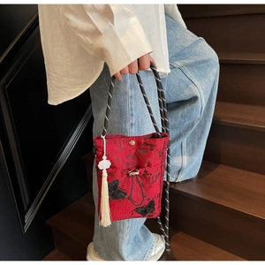 Detailed view of a red Chinese style bucket bag with butterfly embroidery and tassel