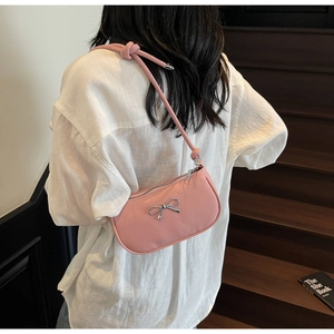 Detail of pink shoulder bag with silver bow accent and knotted strap on model