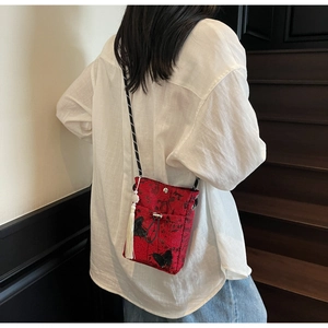 Detail of red jacquard bucket bag with butterfly embroidery and white tassel charm