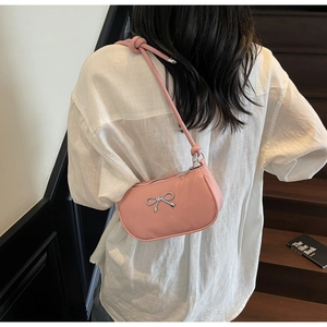Detailed view of pink shoulder bag with silver metallic bow and stylish knot strap detail