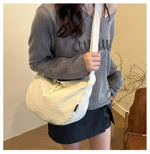 Detail of minimalist beige dumpling crossbody bag with adjustable strap on a model