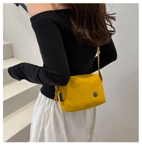 Vue latérale du petit sac bandoulière jaune en nylon avec large sangle sur modèle