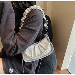 Close-up of silver-gray pleated cloud bag with pearl chain and metallic flower charms