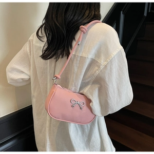 Detail of pink crescent underarm bag with silver bow ornament and slim shoulder strap