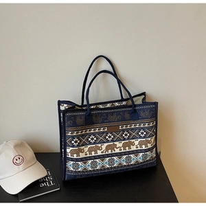 Detail view of ethnic canvas tote bag with bohemian elephant patterns and leather patch