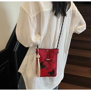 Detail of red lace bucket bag with black butterfly embroidery and white tassel