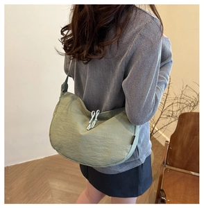 Detail of sage green dumpling bag showing pleated fabric texture and drawstring accents