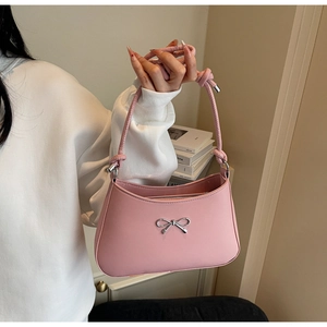 Detail of pink shoulder bag featuring a silver metal bow and woven knot handle design