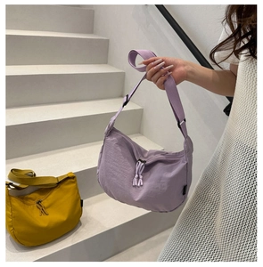 Detail of minimalist nylon dumpling bags in purple and mustard yellow with wide straps