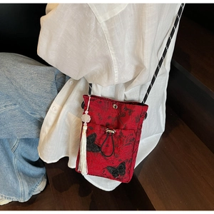 Detail of red jacquard bucket bag with butterfly embroidery, tassels and flower charm