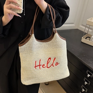 Chic woven tote bag with red Hello embroidery and brown leather handles for beach vacation