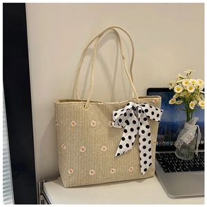 Gros plan du sac fourre-tout en paille avec broderie marguerite et foulard à pois