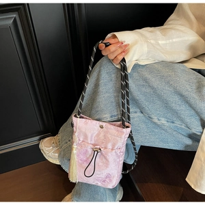 Detail of pink embroidered butterfly pattern and white tassel on the jacquard fabric bag