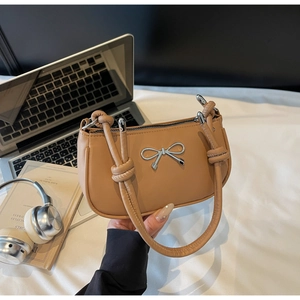Detail of silver metal bow on caramel crescent shoulder bag with knotted handle design
