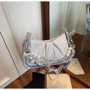 Detail of silver pleated handbag with pearl chain and metallic flower charm detail