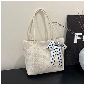 Détail du sac cabas en paille avec broderie marguerite et ruban de soie à pois noir et blanc