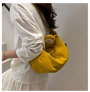 Yellow nylon crescent shoulder bag with a round zip coin purse on a casual model