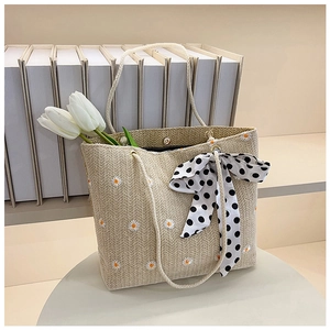 Détail du sac cabas en paille tissée avec marguerites brodées et nœud à pois chic