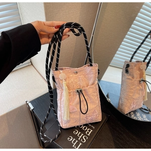 Detail of pink embroidered butterfly pattern and tassel charm on a chic bucket bag