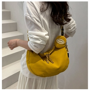 Detail of bright yellow nylon hobo bag with adjustable strap and small round pouch