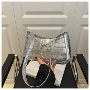Détail du sac à bandoulière argenté à motif crocodile avec nœud métallique chic