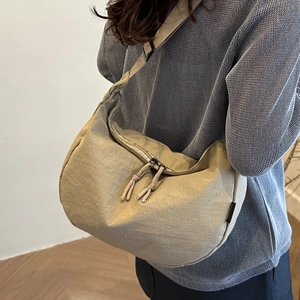 Minimalist beige dumpling shoulder bag with nylon texture shown in a casual lifestyle setting