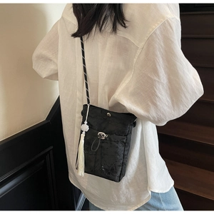 Detail of black butterfly embroidery bag with white pearl tassel and crossbody strap