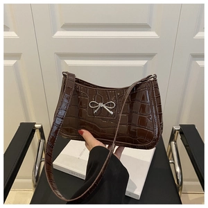 Détail d'un sac sous le bras marron à motif crocodile avec une boucle nœud argentée
