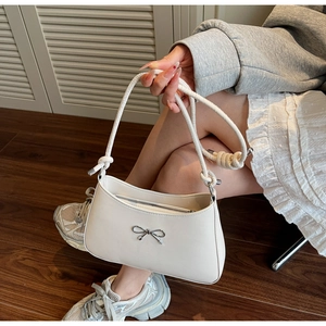 Detail of white underarm bag with silver metallic bow and smooth leather texture