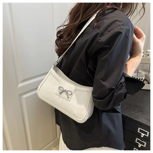Close-up of white crocodile pattern shoulder bag featuring a silver metal bow buckle