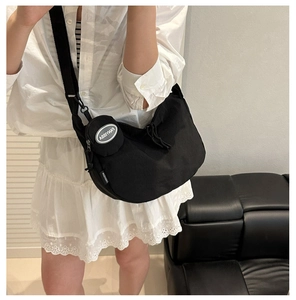 Detail of black nylon tote bag with wide strap and detachable round coin purse accessory