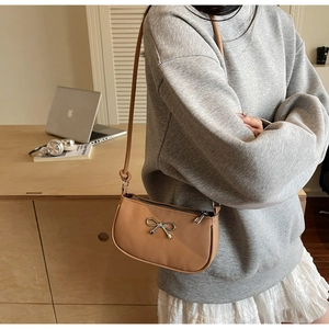 Close-up of camel faux leather crescent bag with silver bow detail and thin shoulder strap