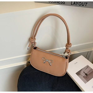 Detailed view of caramel French baguette bag with silver metal bow and knotted strap