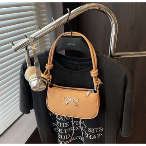 Detail of silver bow accent and knotted handle on beige crescent shoulder bag
