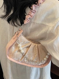 Pink pleated cloud bag with pearl chain and scrunchie strap over a white shirt