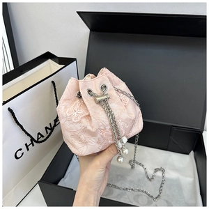 Détail d'un sac seau en dentelle rose avec broderie papillon et pendentifs en perles