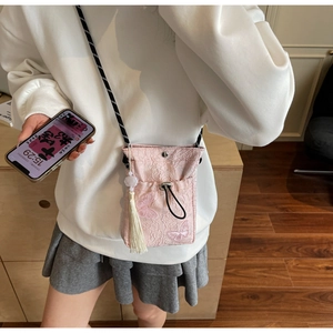 Detailed embroidery of pink butterfly on a traditional bucket bag with tassel