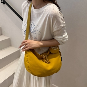 Bright yellow nylon crescent tote bag with detachable coin purse shown on a model