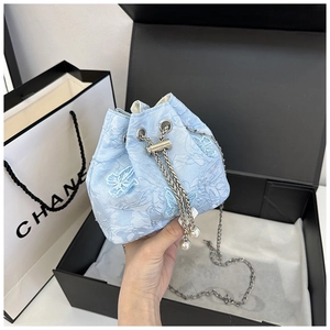 Détail du sac seau en dentelle bleu clair avec broderie papillon et breloques en perles