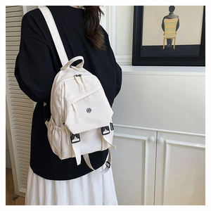 Détail du sac à dos crème minimaliste avec boucle réglable et poche avant zippée