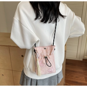 Detail of pink embroidered butterfly bucket bag with tassels and polka dot rope strap