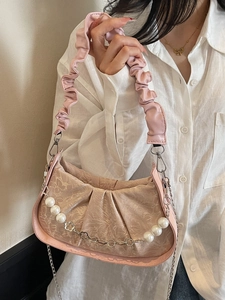 Pink pleated cloud bag with pearl chain and floral accents shown on a model